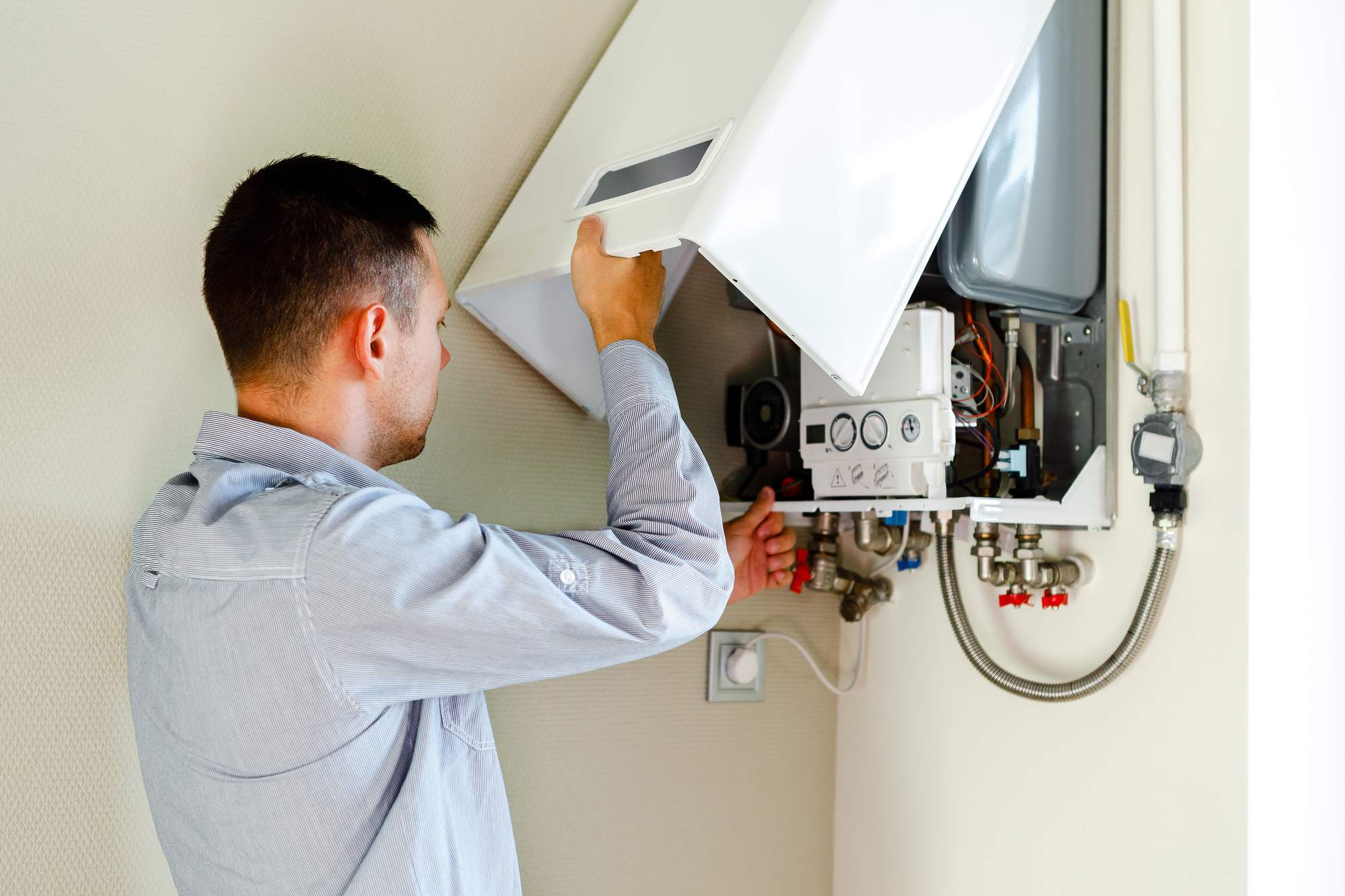 JJK Gas Services engineer opening up a wall-mounted natural gas boiler to begin work